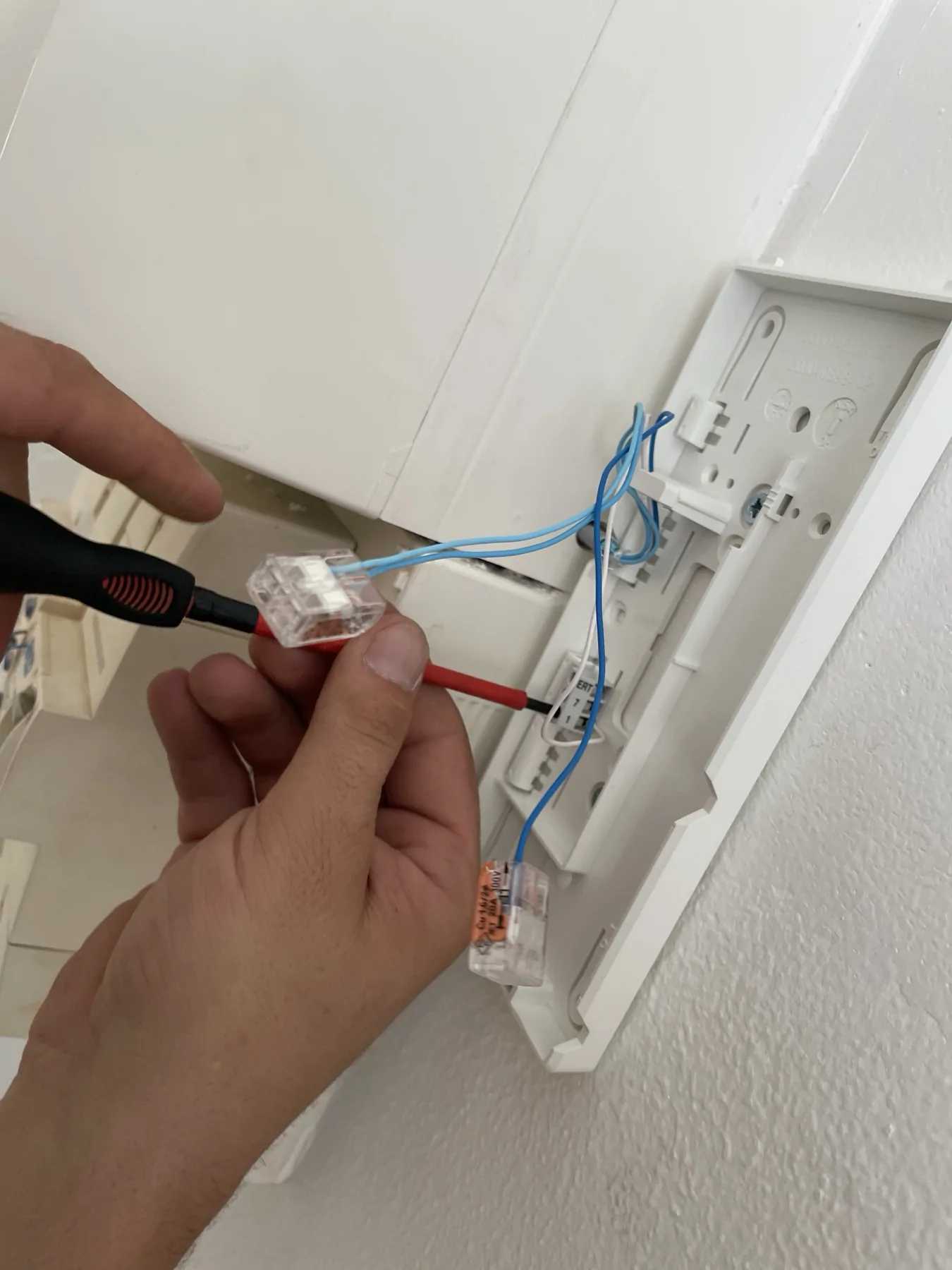 Mains et outil devant les connexions d’un support de moniteur intérieur.
