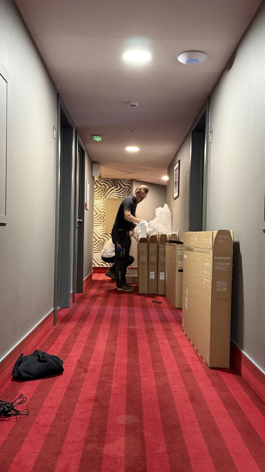 Équipe préparant des téléviseurs et leurs emballages dans un couloir pendant un déploiement.